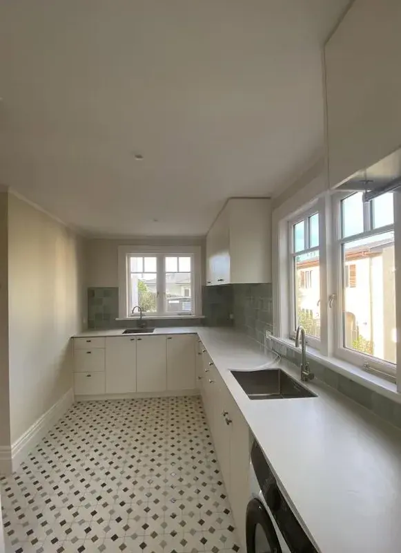 Bright white painted Auckland kitchen with green splashback by Tommy Paint Redo